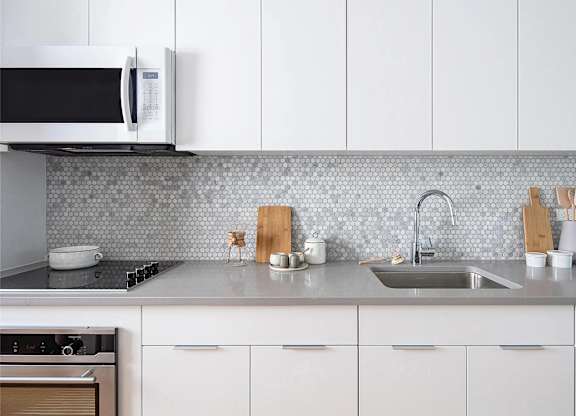 A kitchen with a white microwave, sink, and cabinets.