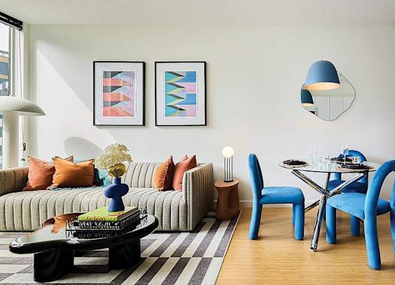 A living room with a sofa, two chairs, a coffee table, and two framed artworks on the wall.