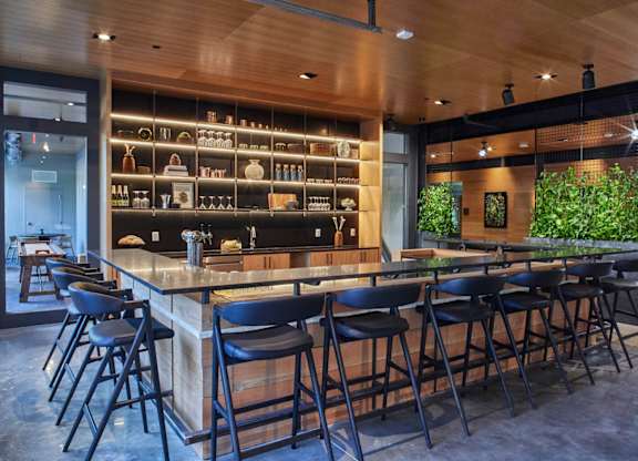 A bar with black stools and a wooden counter.