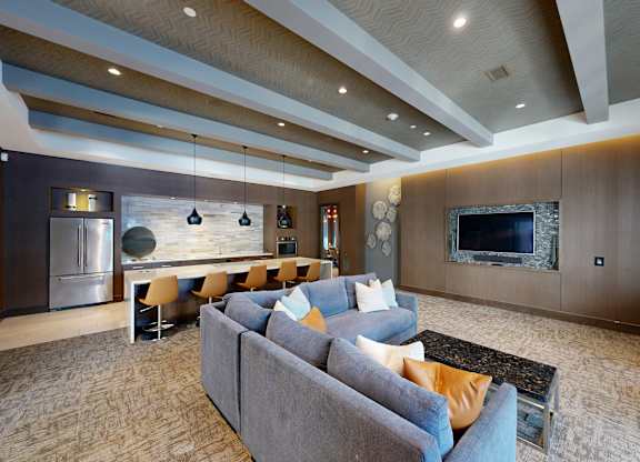 A modern living room with a grey sofa and a wooden ceiling.