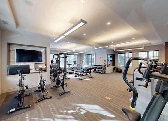 A spacious gym with a variety of exercise equipment and a television.