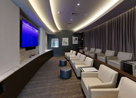 A row of white chairs are lined up in a room with a blue screen on the wall.
