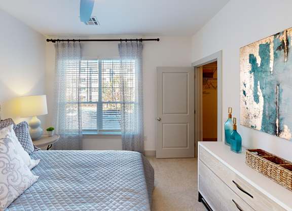 A bedroom with a bed, nightstand, and a painting on the wall.