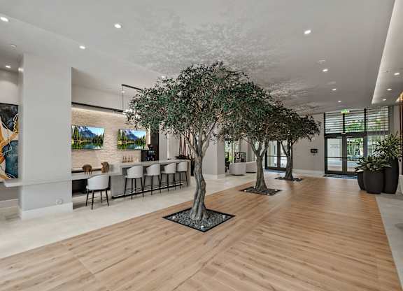 A modern office lobby with a long wooden floor and a row of chairs.