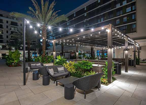 A patio area with a table and chairs under a lit canopy.
