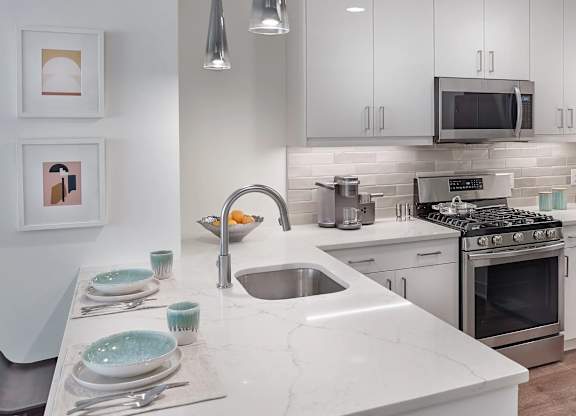 A modern kitchen with a marble countertop and stainless steel appliances.