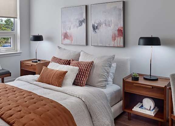 A bedroom with a large bed and two lamps.