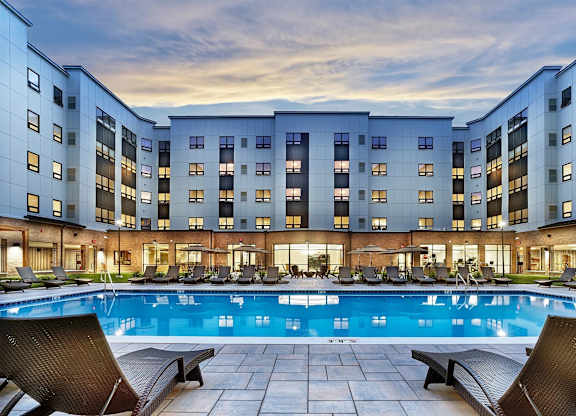 A large swimming pool in front of a multi-story residential building.