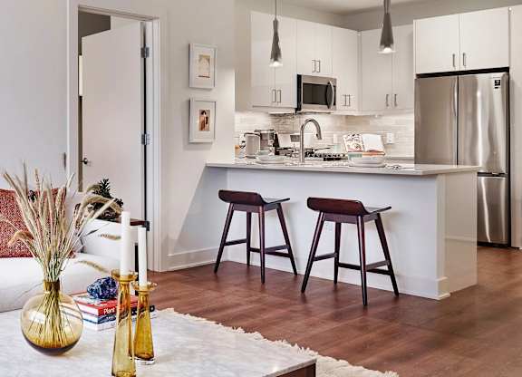 A kitchen with a white counter top and a stainless steel refrigerator.