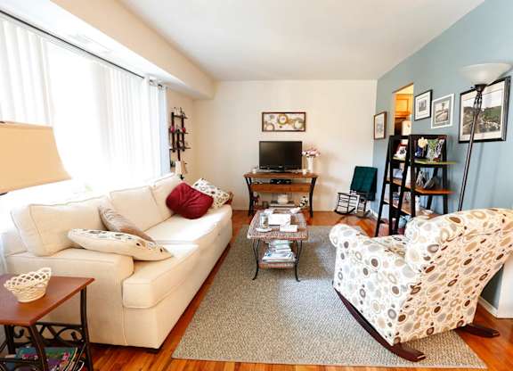 A living room with a white couch and a white chair with a pattern on it.