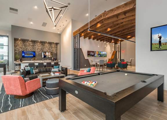 A billiard table is in the middle of a room with a TV on the wall.