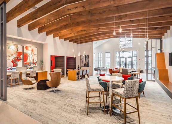 A room with a wooden ceiling and a variety of chairs and tables.