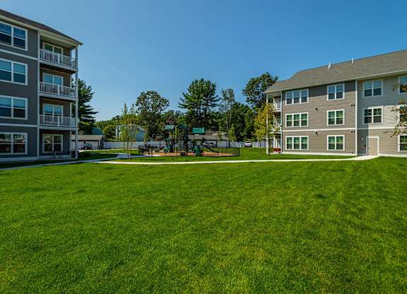 A large grassy field in front of apartment buildings.