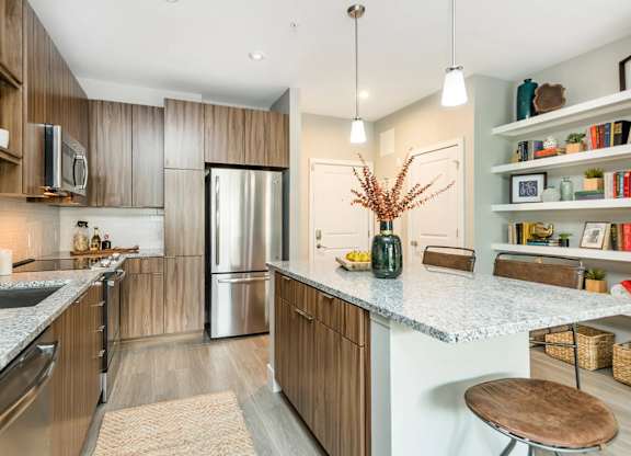 A kitchen with a refrigerator, microwave, and wooden cabinets.