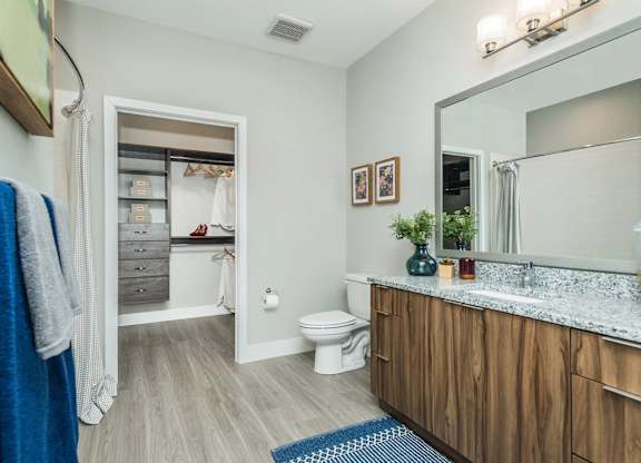 A bathroom with a toilet, sink, and mirror.