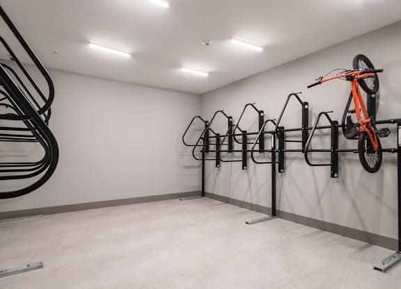A bike rack with multiple bikes, one orange, in a white room.