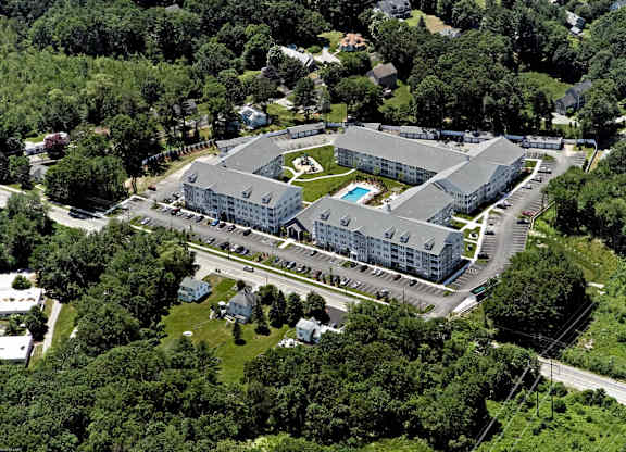 An aerial view of a large building surrounded by trees and a parking lot.