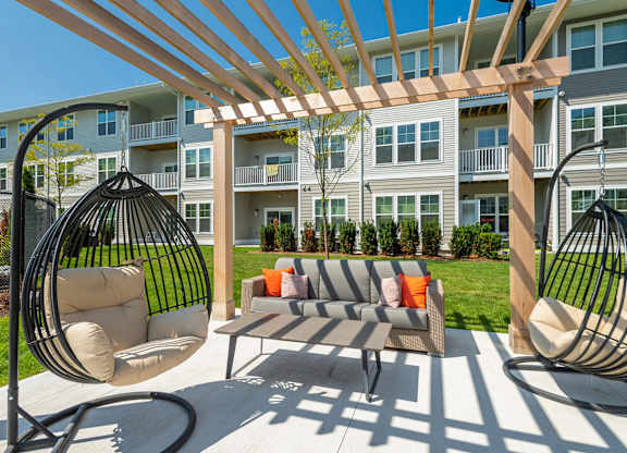 A patio with a swing chair and a table.