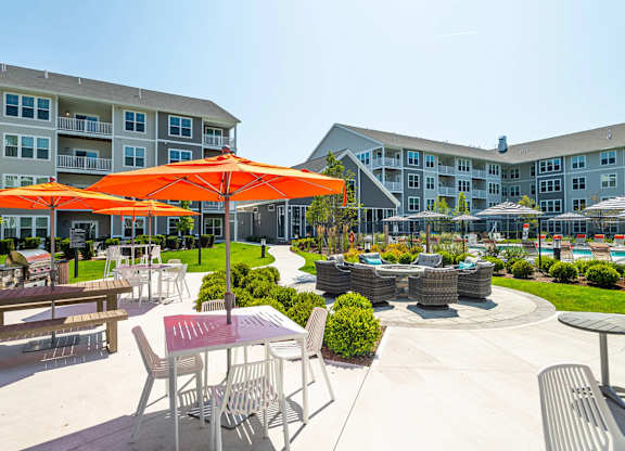A sunny day at the outdoor seating area of a hotel with orange umbrellas and tables.