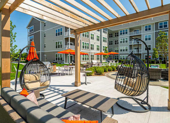 A patio with a white table and two hanging chairs.