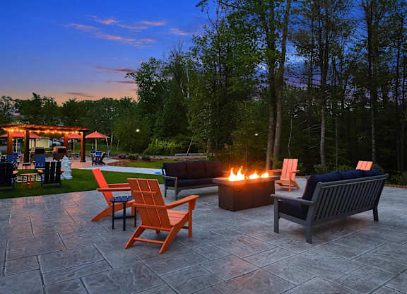 A patio with a fire pit and chairs.