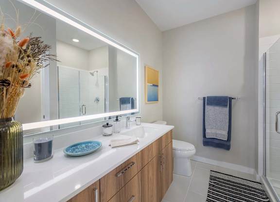 A bathroom with a white counter top and a glass shower door.