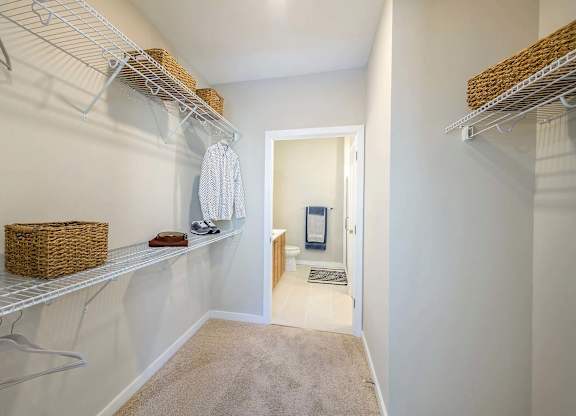 A walk-in closet with white shelves and a basket on the shelf.