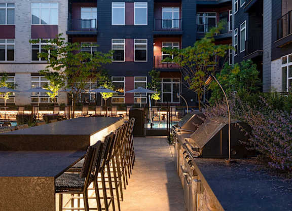 A patio with chairs and tables is surrounded by buildings.