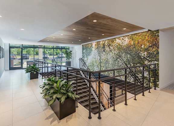A staircase with a metal railing and a plant on the left side.