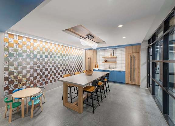A kitchen with a table and chairs in front of a tiled wall.