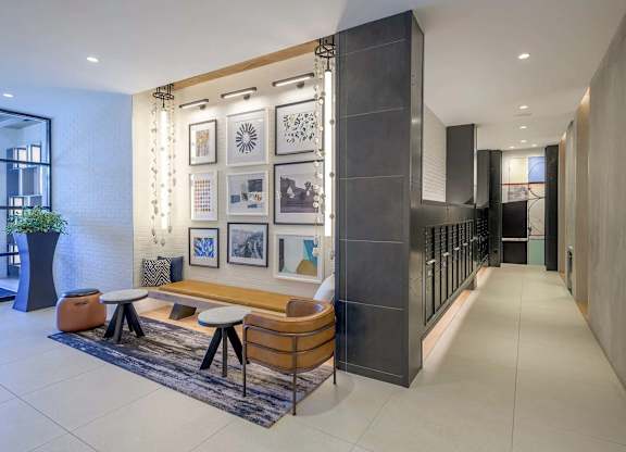 A modern lobby with a wooden bench, a potted plant, and framed pictures on the wall.