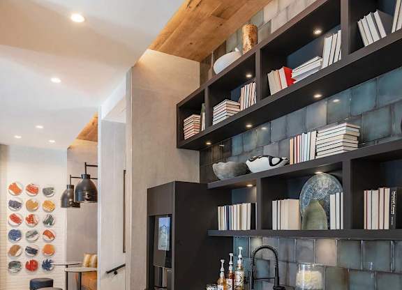 A modern kitchen with a black countertop and wooden shelves.