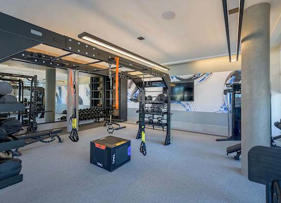 A gym with a variety of equipment including a squat rack, bench press, and a box on the floor.