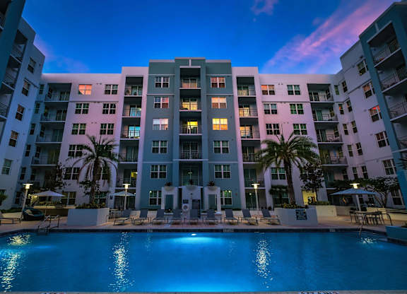 A large apartment building with a pool in front of it.