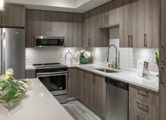 A modern kitchen with a stainless steel refrigerator, microwave, and dishwasher.