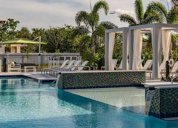 A pool with a waterfall and a white canopy.