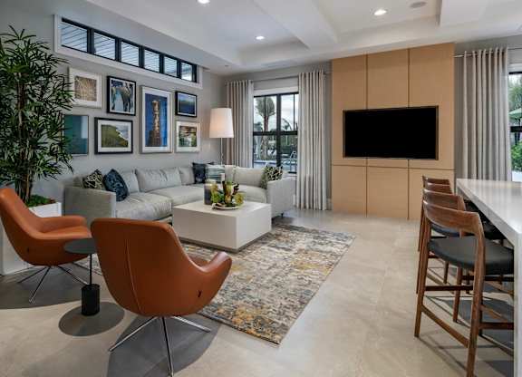 A living room with a grey couch, a brown chair, a white coffee table, a flat screen TV and a rug.