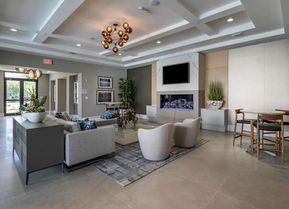 A modern living room with a grey sofa, a white armchair, a TV, and a fireplace.