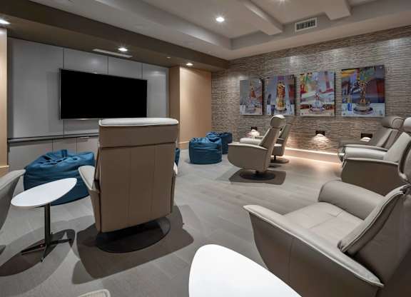 A modern lounge area with a television, comfortable seating, and artwork on the walls.