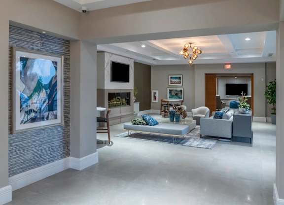 A spacious living room with a grey sofa set and a large abstract painting on the wall.