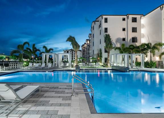 A swimming pool surrounded by palm trees and a building in the background.