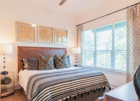 A bedroom with a bed, pillows, and a ceiling fan.