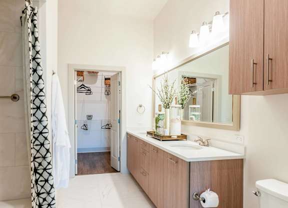 A bathroom with a white tub, wooden cabinets, and a large mirror.