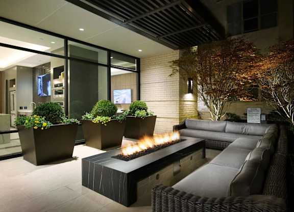 A modern outdoor seating area with a fire pit and comfortable couches.