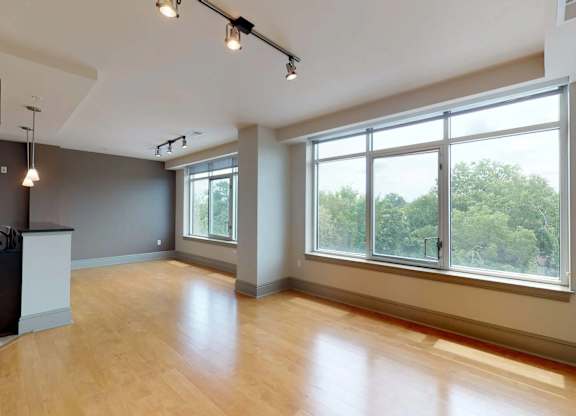 A spacious room with wooden floors and large windows.