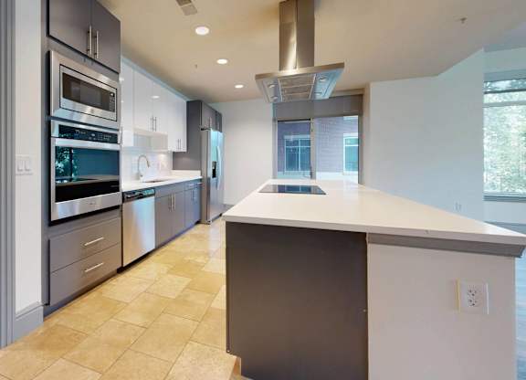 A modern kitchen with a large island and stainless steel appliances.