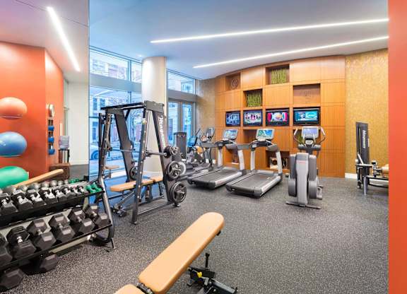 A gym with a variety of equipment including treadmills, weights, and exercise machines.