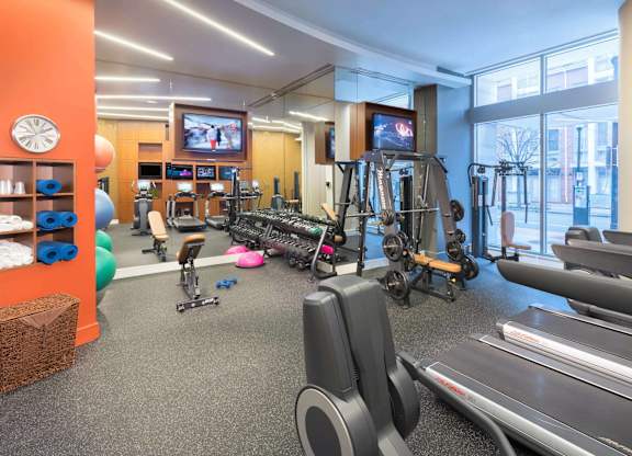 A gym with a variety of equipment including treadmills, weights, and exercise machines.