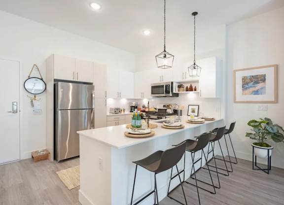 A modern kitchen with a white island and black barstools.