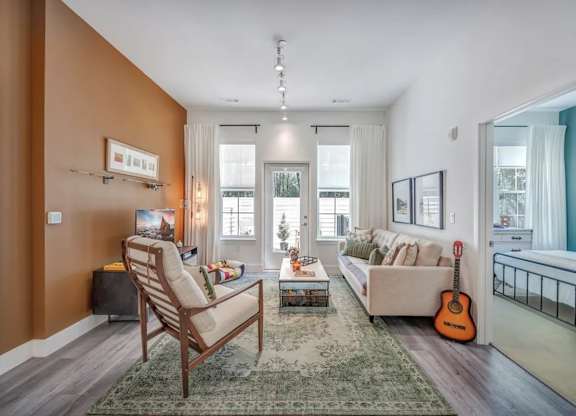A living room with a chair, a couch, a rug, and a guitar.
